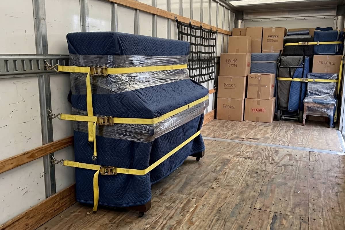 Upright piano wrapped and secured on dolly by professional piano movers in Markham